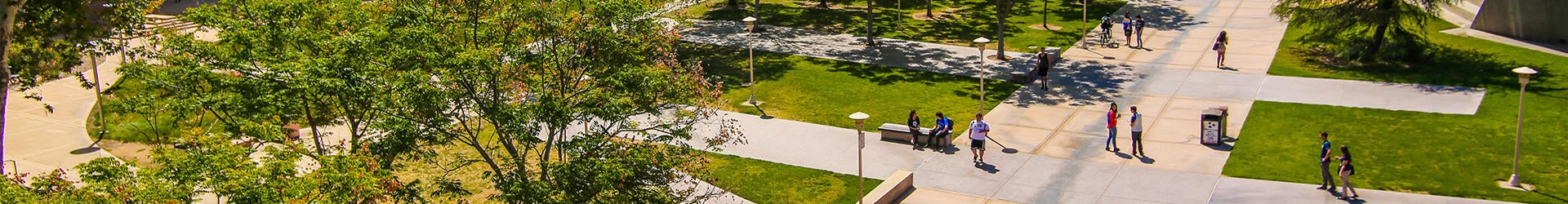 Aerial view of UCR's parklike campus and students walking to class and hanging out on a sunny day.